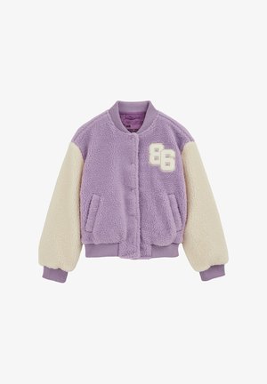 Purpurinė kailinė striukė su pieno spalvos rankovėmis, pūstais rankogalais ir sagų užsegimu priekyje. Kairėje krūtinės pusėje yra aplikacija su skaičiumi '86'.