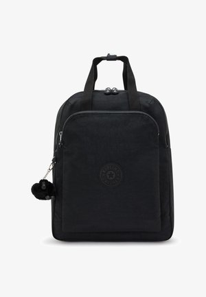 Mochila de tela negra con forma redondeada, que cuenta con un bolsillo frontal con cremallera, parche con logo y un pequeño llavero de mono peludo. Textura suave.