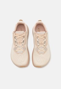 Light pink athletic shoes with a textured upper, mesh detailing, and contrasting beige sole. Laces in a zigzag pattern and logo accent.