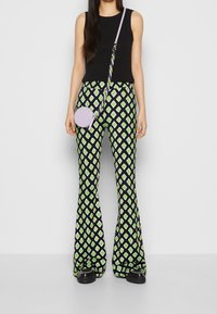 Czarny top bez rękawów, wzorzyste spódnice w kolorze granatowym z zielonymi diamentami oraz okrągła lawendowa torebka na ramię z plecionym paskiem.