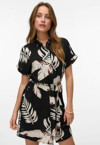 Abito nero a camicia con maniche corte, caratterizzato da una stampa foglie beige e bordeaux. Include una cintura da annodare e una chiusura frontale con bottoni.