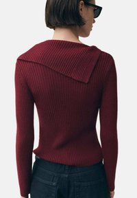 Maglione bordeaux a coste con dettaglio di colletto ampio, caratterizzato da maniche lunghe e corpo aderente, abbinato a pantaloni in denim scuro.