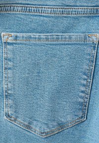 Tylna kieszeń jasnoniebieskich dżinsów z widocznym pomarańczowym przeszyciem i fakturą tkaniny.