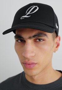 Black cap with a curved brim, featuring a prominent white "L" logo. Mesh back for breathability, minimalistic design, and adjustable strap.