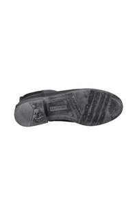 Suela de bota de cuero negro con agarre de goma texturizado, que presenta líneas horizontales y verticales. Marca visible en la entresuela.