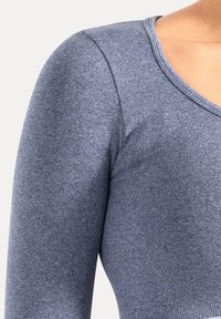 Langærmet, V-udskåret top i en meleret marineblå strik. Har en figursyet silhuet med ribbet kant og glat tekstur.