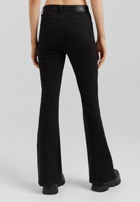 Mustat leveälahkeiset farkut, joissa on keskipitkä vyötärö, valmistettu denimmateriaalista. Ominaisuuksiin kuuluu kaksi takataskua ja sileä pinta, viimeistelty logopatchilla vyötärönauhassa.