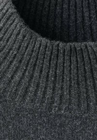 Tejido de suéter de punto en gris oscuro que presenta una textura acanalada, con un cuello alto y una apariencia esponjosa. Se pueden ver costuras de precisión.