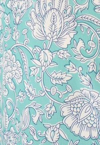 Tissu floral présentant des motifs bleu et blanc avec de grandes fleurs et des motifs de feuilles complexes sur un fond bleu-vert clair.