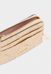 Portafoglio in pelle dorata con texture, dotato di chiusura lampo, logo impresso, diversi scomparti per carte e una fodera interna liscia.