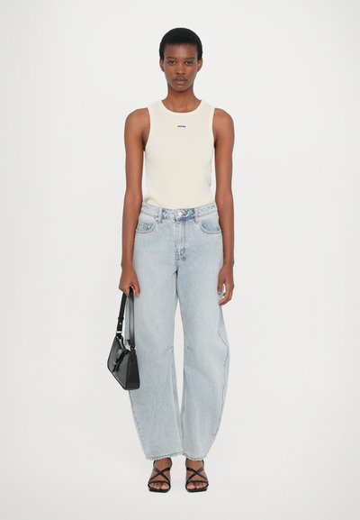 Crème gebreide mouwloze top, lichtblauwe jeans met hoge taille, zwarte sandalen met kruisbanden en een kleine zwarte handtas, met een relaxte pasvorm en subtiele details.