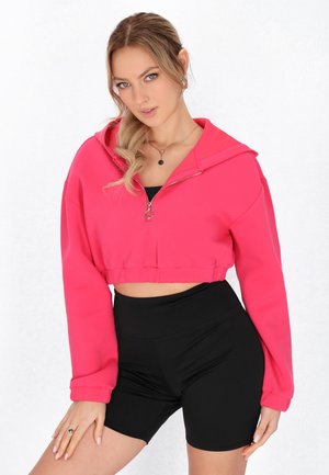 Korte lynlås hoodie i klar pink bomuld, med hætte, lange ærmer og elastisk kant, parret med høj Talje sorte shorts.