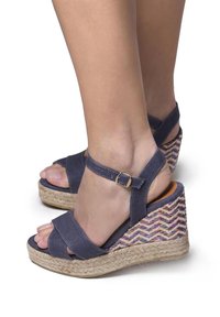 Kengät wedgenokilla, joissa on denim päällinen, säädettävä nilkkahihna ja kudottu monivärinen kuvio korkokengän kantapäässä. Matalapohjainen malli, rento istuvuus.