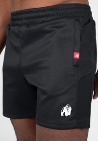 Zwarte sportshorts gemaakt van lichtgewicht stof met een elastische tailleband. Bevat een zijzak en een wit gorilla-logo op de zoom.