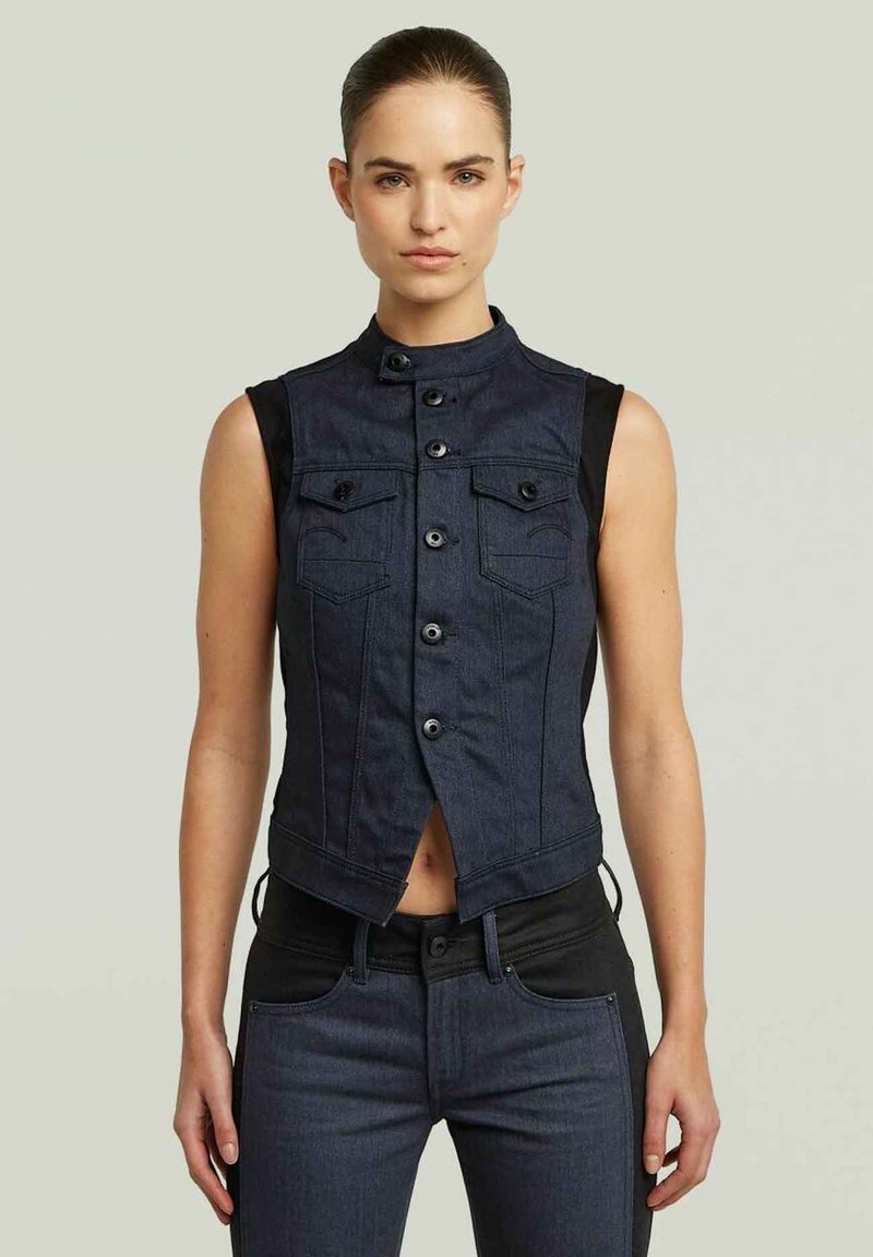 Gilet senza maniche in denim blu scuro, con colletto alto, chiusure a bottoni, tasche frontali e pannelli laterali neri per contrasto.