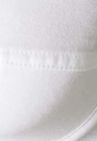 White cotton fabric with a smooth texture, featuring flat seams and a subtle ribbed pattern. The material appears lightweight and stretchy.