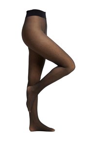 Collants noirs translucides avec un petit motif à pois, présentés sur des jambes croisées sur fond blanc.