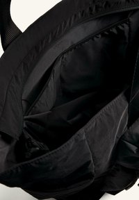 Fekete szövet bevásárlótáska sima textúrával, nagy, nyitott belső résszel és cipzáras záródással a tetején.