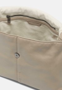 Borsa in pelle beige con tasca interna con zip, foderata in tela crema a contrasto e dettaglio con bottone a pressione. Superficie strutturata con design elegante.