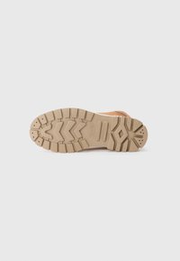 Semelle de botte de randonnée marron en caoutchouc avec des rainurages profonds. Présente un design texturé et des rainures accentuées pour une adhérence et une durabilité accrues.