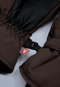 Rjava izolirana rokavica s teksturirano črno notranjo podlogo, elastičnimi zapestji in črnim nastavljivim trakom. Opremljena z rdečo etiketo Primaloft.