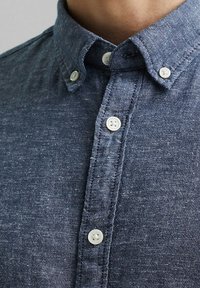 Donkerblauw overhemd met knopen van een textuurstof, met een kraag en witte knopen langs de voorkant.