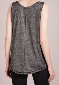 Top senza maniche in tessuto nero glitterato, con orlo arrotondato e scollatura a V. Il retro presenta una cucitura centrale e una texture liscia.