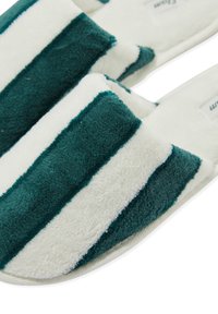 Zielono-białe kapcie w paski, wykonane z miękkiego, teksturowanego materiału, z wyściełaną wkładką i otwartym noskiem.