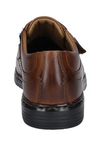 Brown leather shoe with a rounded shape and visible stitching. Interior padded lining and a textured black sole. Casual design.