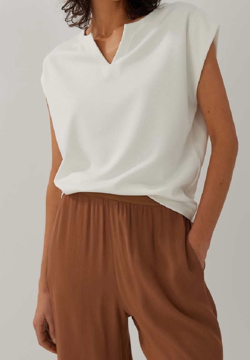 Haut blanc à manches courtes avec un col en V et une coupe décontractée, assorti à un pantalon marron à large jambe en tissu doux.