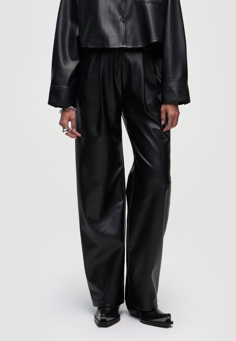 Zwarte leren broek met wijde pijpen, een gladde textuur en een hoge taille. Het ontwerp heeft plooien en wordt gecombineerd met een cropped top.