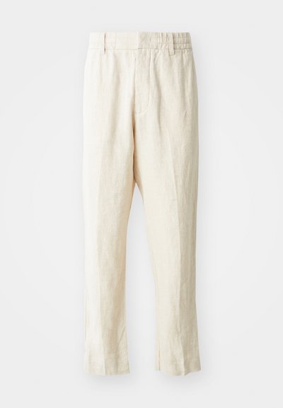 Μπεζ λινές παν trousers με άνετη εφαρμογή, κωνικά πόδια και επίπεδο μπροστινό μέρος. Διαθέτουν ελαστική μέση για άνεση και ελάχιστη λεπτομέρεια ραφής.