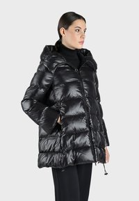 Giubbotto imbottito in finta piuma di colore nero lucido, dotato di cappuccio, chiusura con zip e tasche laterali. Progettato con una silhouette ampia e polsini a coste.