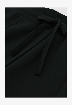 Čierne bavlnené jogger nohavice s elastickým pásom a sťahovacou šnúrkou. Tkanina má hladkú textúru s jemnými švovými detailmi.