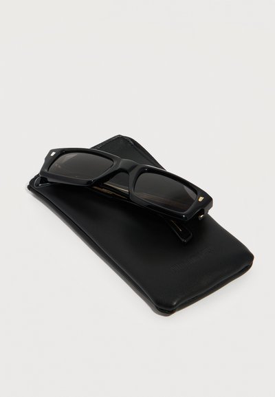Zwarte rechthoekige zonnebril die rust op een zachte zwarte leren hoes tegen een witte achtergrond.