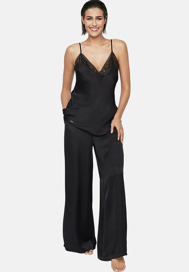 Zwart satijnen pyjama set met een kant afgewerkte camisole met dunne bandjes en wijdvallende, losse broek. Soepele textuur en elegante uitstraling.