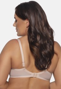 Reggiseno beige chiaro con spalline regolabili e chiusura a gancio. Caratterizzato da un tessuto morbido e pannelli trasparenti lungo il band per un design discreto.