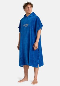 Blå hætteponcho lavet af blød frotté, med korte ærmer, sideslids og broderet logo på brystet.