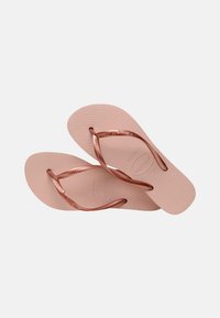 Ζευγάρι ανοιχτόροζ σαγιονάρες με υφή στην σόλα και λαμπερές ροζ χρυσές λωρίδες, τοποθετημένες επικαλυπτόμενες σε απλό λευκό φόντο.