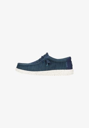 Scarpa casual slip-on blu navy con tomaia in maglia, suola bianca maculata e chiusura elastica a lacci su sfondo bianco.