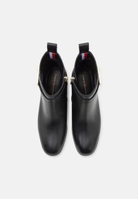 Schwarze Leder-Ankle-Boots mit goldenen Hardware-Details, runder Zehenpartie und einer gemusterten Stoffschlaufe hinten. Das Innenfutter weist das Markenlogo auf.