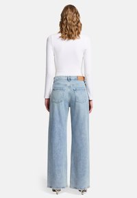Jeans a gamba larga azzurro chiaro con vita alta, realizzati in denim. Sul retro presentano due tasche e una toppa in pelle in vita.