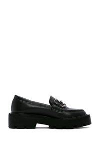 Mocassins en cuir noir avec une semelle plate-forme épaisse, une accent de quincaillerie métallique sur la sangle, et une texture lisse avec un design à bout rond.