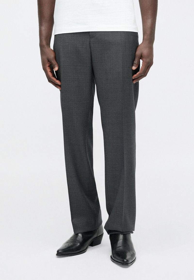 Grijze op maat gemaakte broek met een gestructureerde afwerking, voorzien van een platte voorkant en rechte pijpen, gecombineerd met zwarte leren schoenen.
