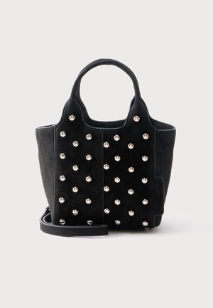 Čierna kabelka z semišu so okrúhlymi striebornými cvokmi, dvoma krátkymi rúčkami a odnímateľným ramenným popruhom na bielom pozadí.
