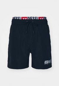 Navy swim shorts made of lightweight material featuring an elastic waistband with a drawstring and a white logo on the lower side.