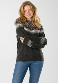 Gray knitted sweater with a fair isle pattern in black, white, and pink. Features long sleeves and a round neckline. Paired with blue jeans.