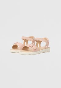 Sandales roses à bout ouvert, avec des sangles ajustables et un design minimaliste. Elles présentent une surface texturée et une semelle de couleur claire.
