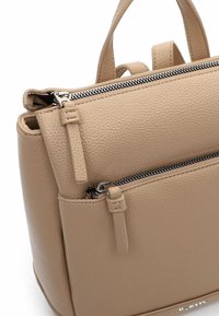 Beżowa skórzana torebka o teksturowanej powierzchni, z dwoma górnymi uchwytami i zasuwaną kieszenią z przodu. Ozdobiona srebrnymi detalami metalowymi.