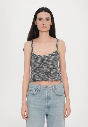 Grå, kort tanktopp med spaghetti-stropper, med et teksturert mønster og slitt detaljering i kanten. Kombinert med lyseblå jeans.
